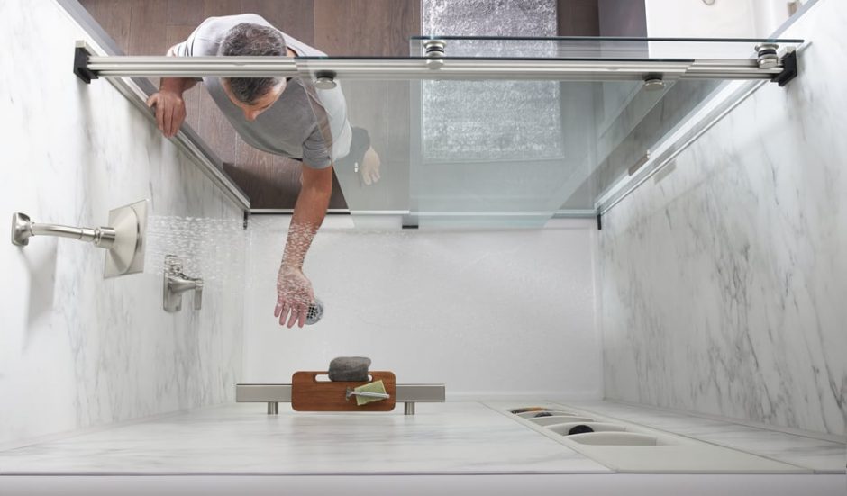 Person reaching into shower with water running to test temperature