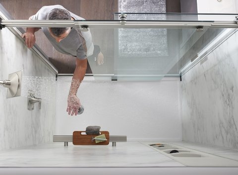 arial view of man standing outside shower feeling water temperature